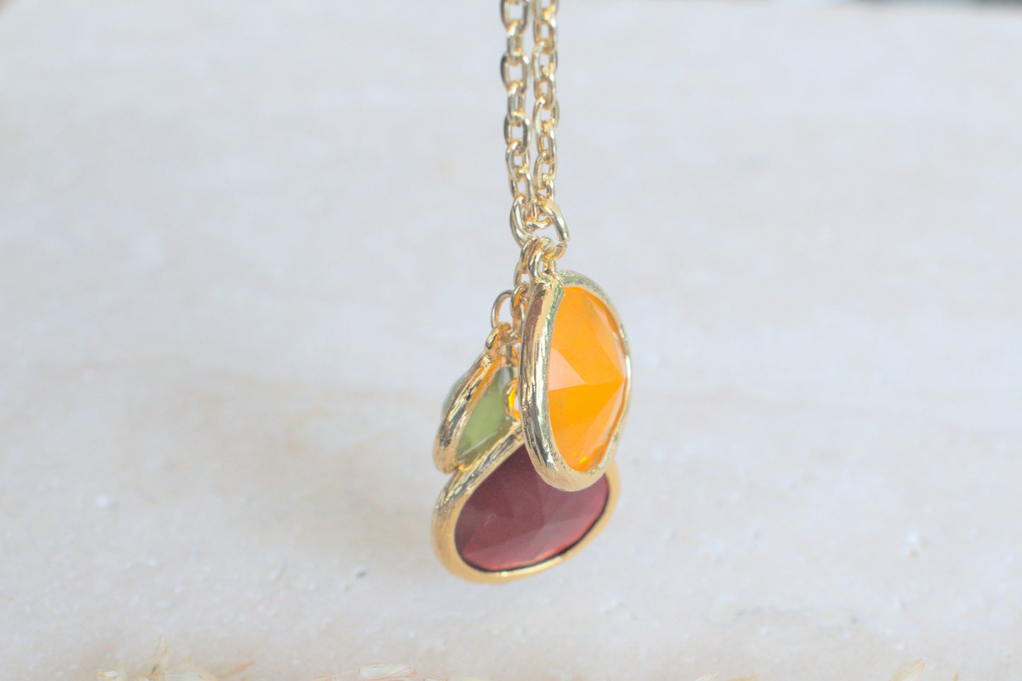 Goldene Kette mit bunten Steinen in verschiedenen Längen grün, orange und schwedenrot