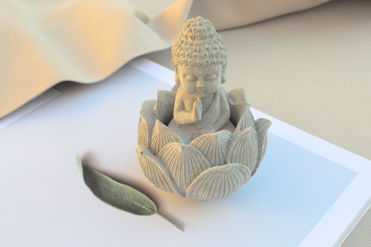 Kleiner Budda mit Lotusblüte aus grauem Beton für Ruhe beim Yoga