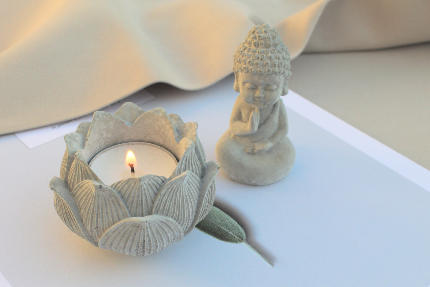 Kleiner Budda mit Lotusblüte aus grauem Beton für Ruhe beim Yoga